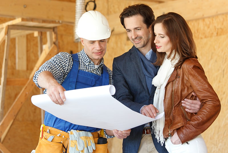 couple with construction worker looking at blueprints